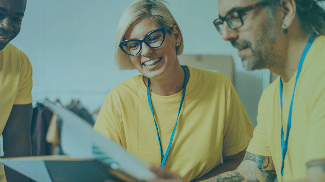 Women and man smiling while looking at paperwork